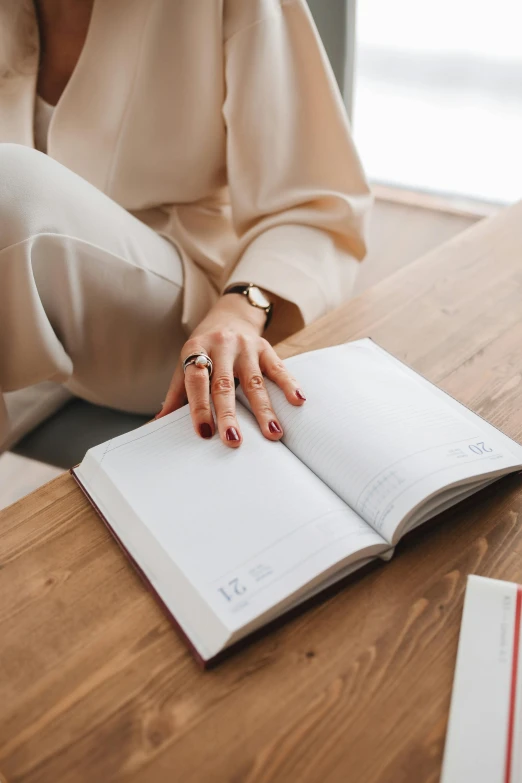 a woman sitting at a table reading a book, trending on pexels, diary on her hand, detailed professional, lightly dressed, white