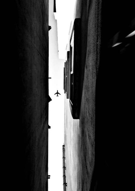 a black and white photo of a narrow street, inspired by Sergio Larraín, minimalism, airplane, silhouette :7, simone graci, distance view