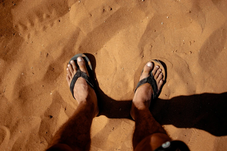a person standing on top of a sandy beach, by Daniel Seghers, pexels contest winner, hurufiyya, flip flops, in the australian outback, well shaded, more tan face