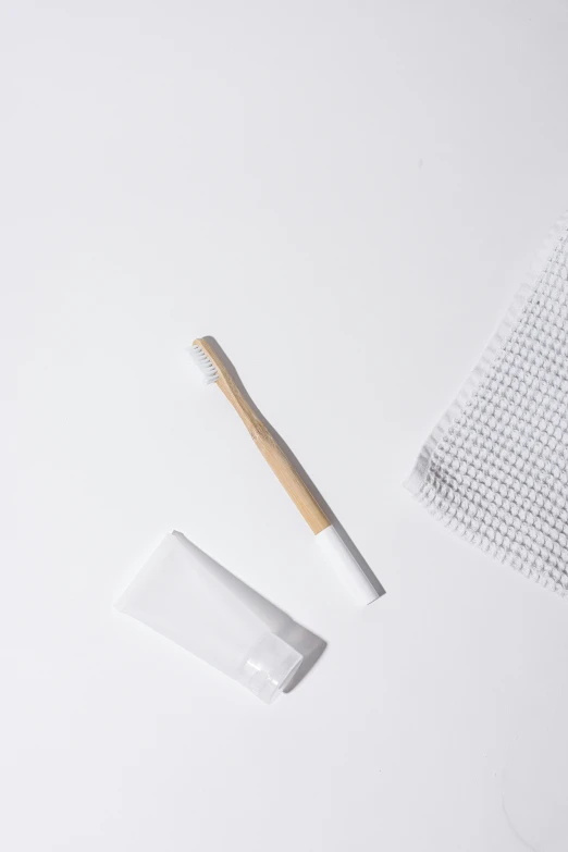 a toothbrush sitting on top of a white table, white cloth, made of bamboo, one disassembled, set against a white background