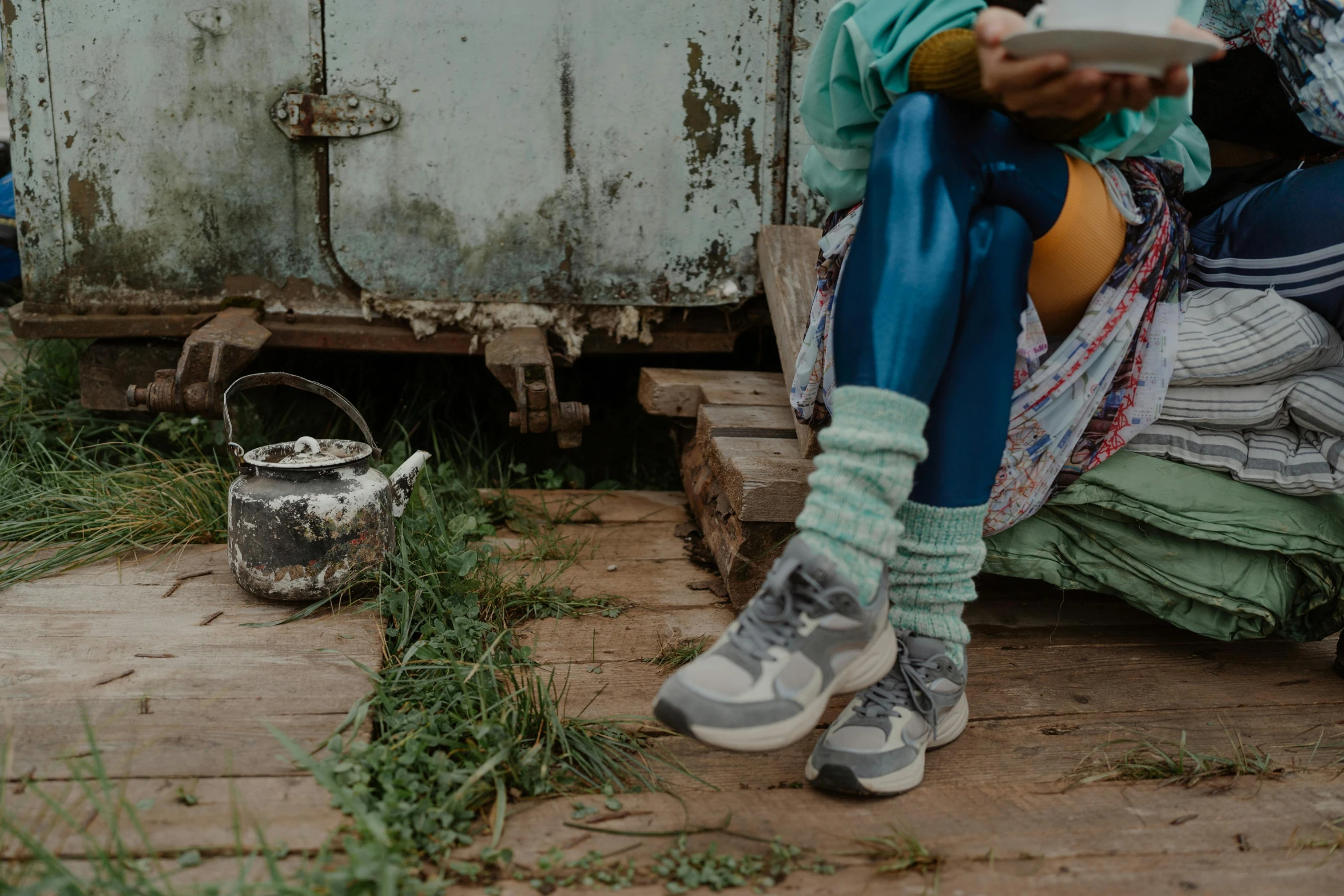 a woman sitting on the ground holding a plate, by Daniel Lieske, trending on unsplash, acid-green sneakers, next to an rv, village girl reading a book, upcycled