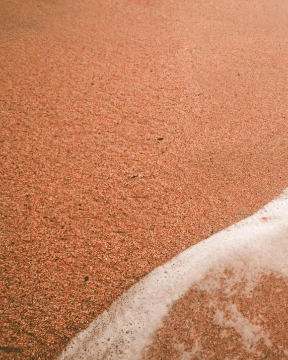 a tennis ball sitting on top of a tennis court, red sand beach, cover image, pale pink grass, sandworm