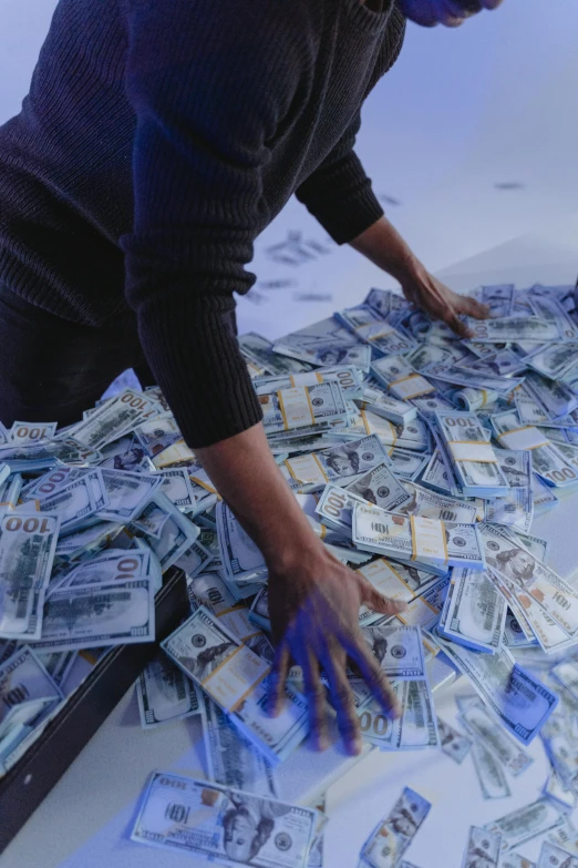 a man standing over a pile of money on top of a table, by artist, trending on unsplash, conceptual art, huge holograms, aida muluneh, icy, photograph credit: ap