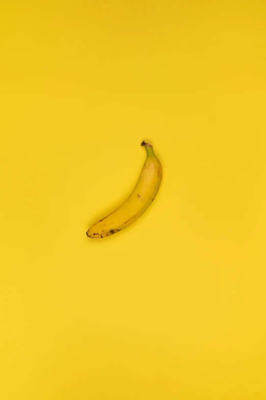 a banana sitting on top of a yellow surface, by Andrew Domachowski, shot on hasselblad, high-resolution, ruan ji, a colorful