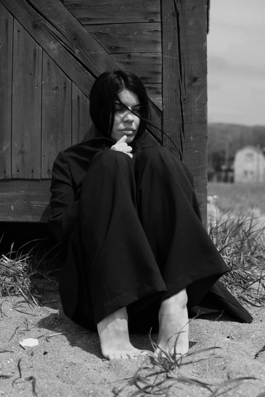 a black and white photo of a woman sitting on the ground, inspired by Yamagata Hiro, wearing black wizard robes, murdoc niccals, billie eilish, lonely and sad
