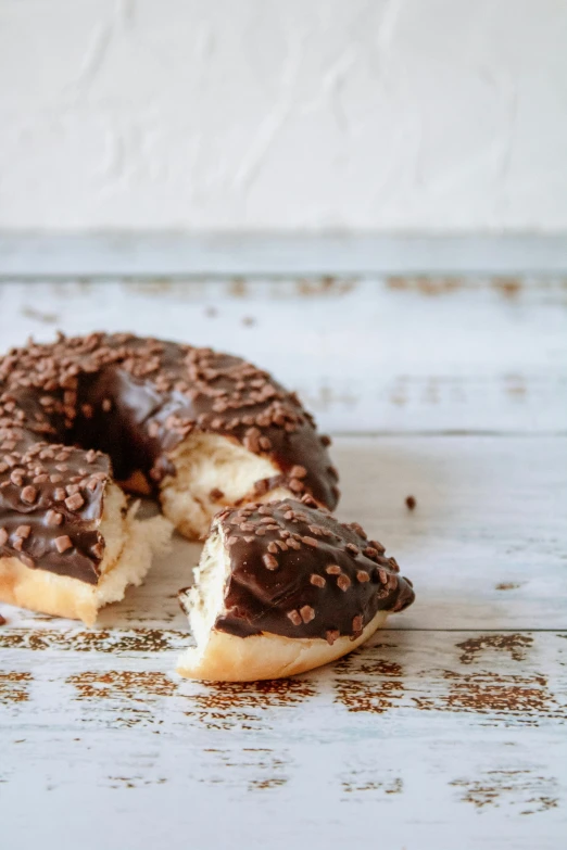 a chocolate donut with a bite taken out of it, by Nicolette Macnamara, hurufiyya, on wood, sprinkles, sicilian, rococco