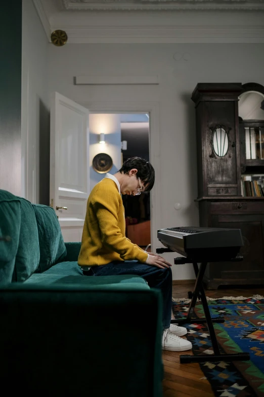 a man sitting on a couch in a living room, an album cover, inspired by Fei Danxu, pexels contest winner, playing piano, teenage boy, shot with sony alpha 1 camera, in spain