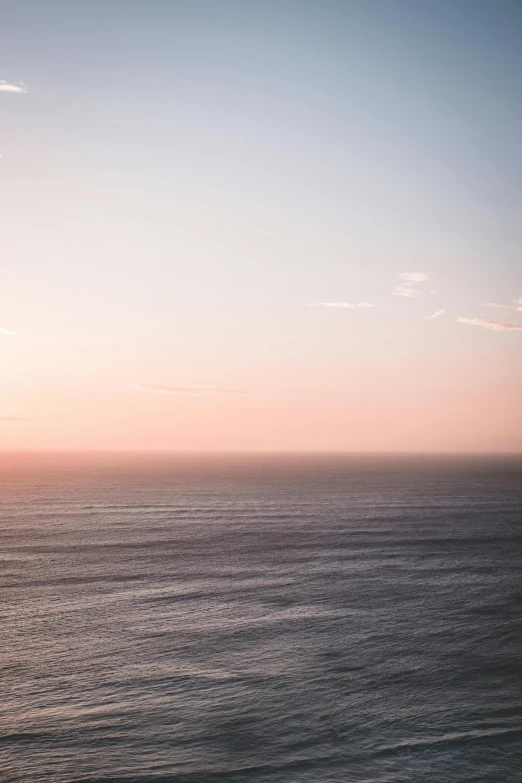 a large body of water next to a beach, unsplash contest winner, romanticism, faded pink, sunset light, clean horizon, without text