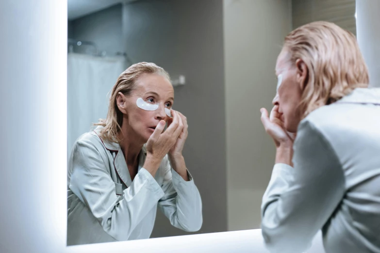 a woman shaving her face in front of a mirror, by Dietmar Damerau, pexels contest winner, wrinkled face, white facepaint, doctors mirror, then another