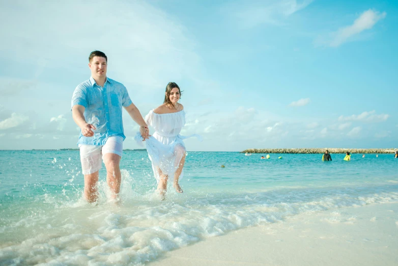 a man and a woman are running in the water, a photo, pexels contest winner, aruba, white and teal garment, youtube thumbnail, tourist photo