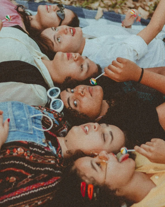a group of people laying on top of a blanket, trending on pexels, 1970s philippines, queer woman, teenagers, profile image