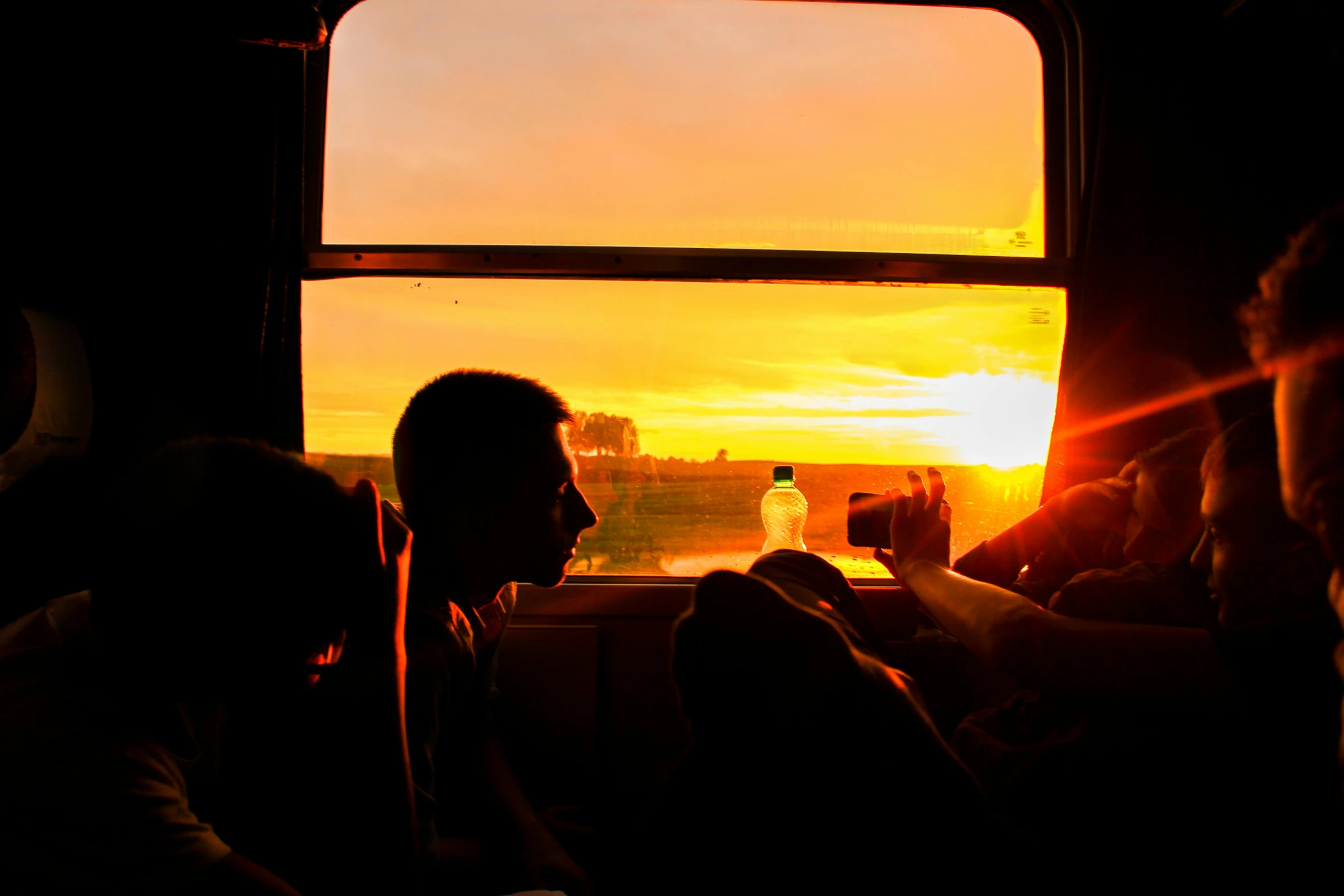 a group of people sitting next to each other on a bus, by Lucia Peka, pexels contest winner, orange sunset, train window, instagram post, rectangle