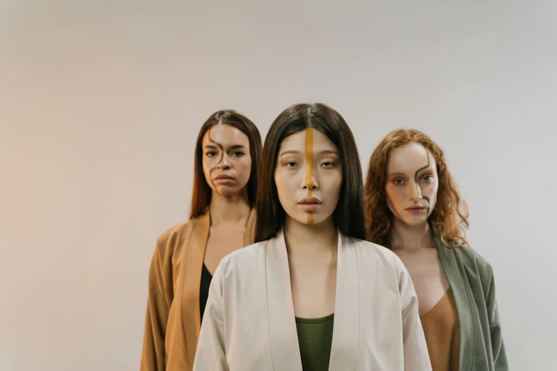 a group of women standing next to each other, inspired by Kim Tschang Yeul, trending on pexels, hyperrealism, neanderthal people, ochre, the three fates, serene expression