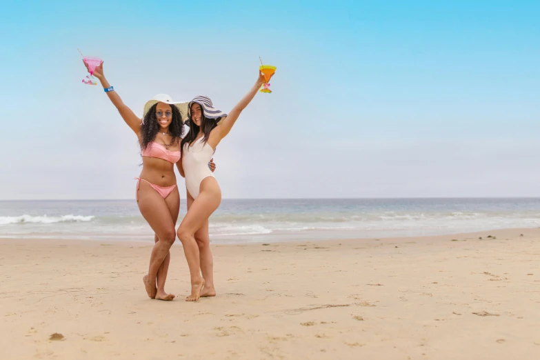 a couple of women standing on top of a sandy beach, lizzo, booze, round thighs, celebrating