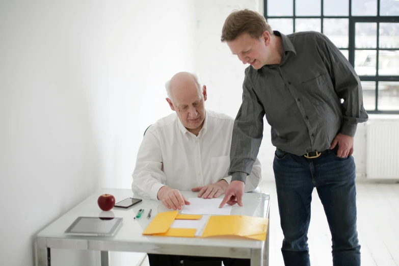 a couple of men standing next to each other at a table, unsplash, norman foster, pen and paper, neurograph, colour photograph