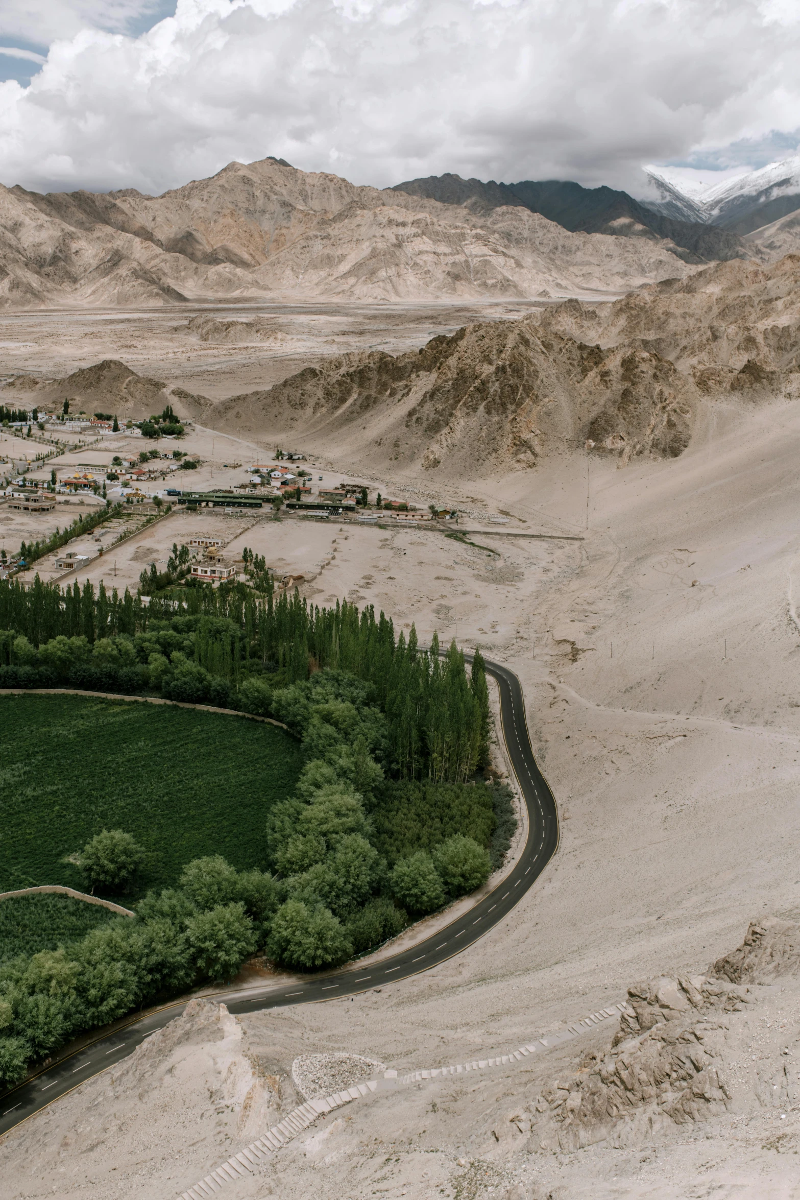 a river running through a lush green valley, inspired by Steve McCurry, trending on unsplash, land art, sand storm, houses and roads, tibet, high detail photo of a deserted
