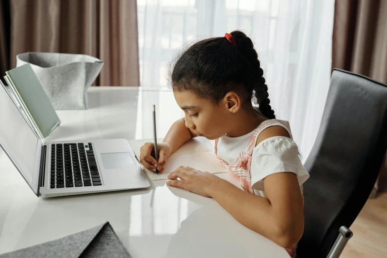 a little girl sitting at a desk with a laptop, pexels contest winner, pen and paper, indian girl with brown skin, bending down slightly, youtube thumbnail