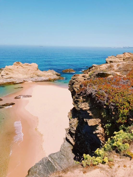 a sandy beach next to a body of water, orange rocks, shades of pink and blue, portugal, high view