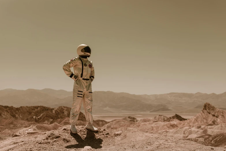 a man in a space suit standing on top of a hill, a colorized photo, pexels contest winner, sepia colors, mars vacation photo, full costume, a person standing in front of a