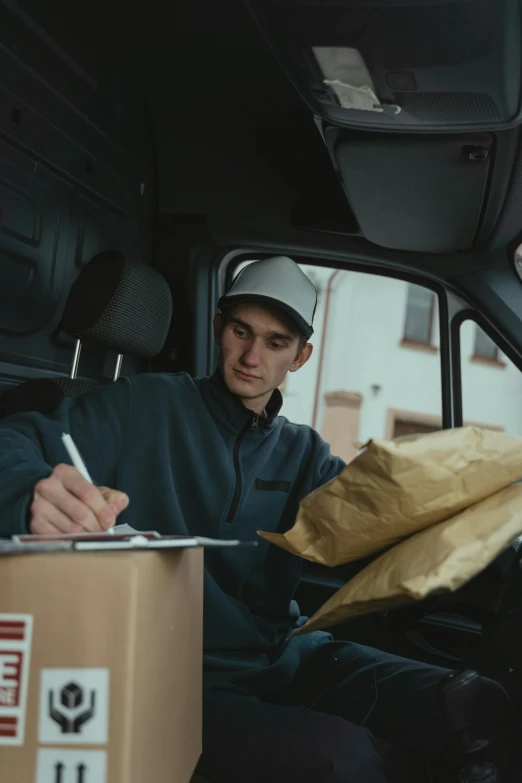 a man sitting in the back of a van writing on a piece of paper, delivering parsel box, worksafe. cinematic, avatar image, ignant