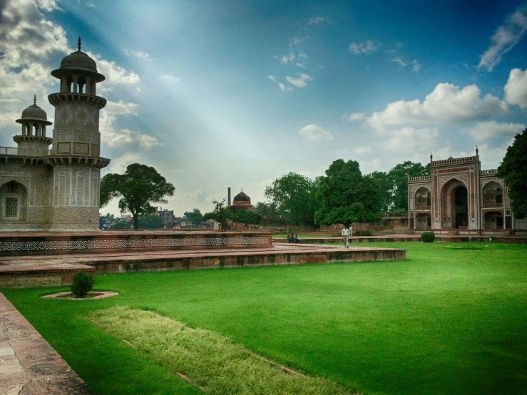 a green lawn with a building in the background, unsplash contest winner, hurufiyya, ancient india, fountains and arches, tombs, panoramic widescreen view