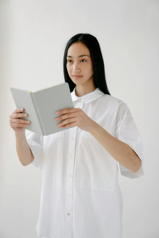 a woman in a white shirt holding a book, by helen huang, curated collections, kiko mizuhara, healthcare, short sleeves