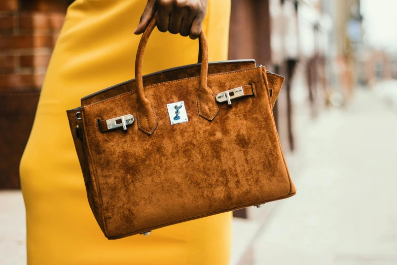 a woman in a yellow dress holding a brown handbag, pexels contest winner, highly textured, highly polished, with brown skin, hermes ad