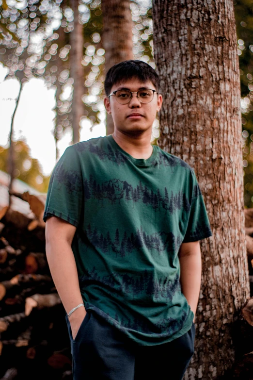 a man standing in front of a pile of wood, by Robbie Trevino, wearing a marijuana t - shirt, forest backdrop, asian male, profile image