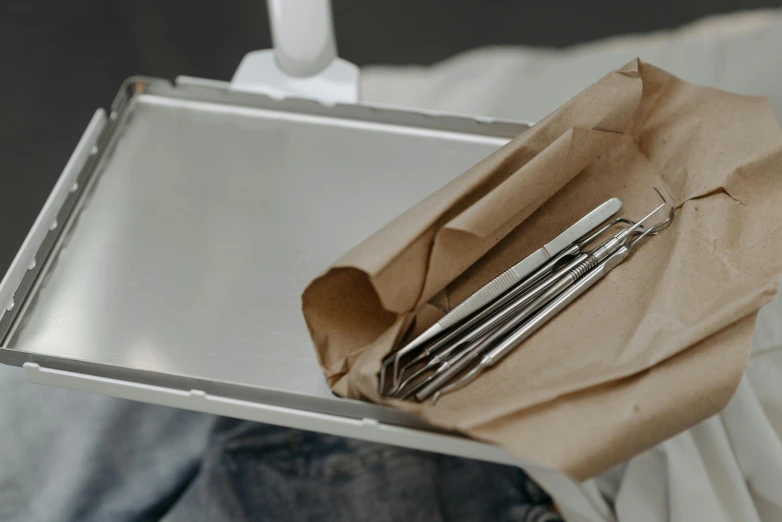 a person holding a tray with utensils in it, trending on pexels, arbeitsrat für kunst, surgical iv bag, metal teeth, stainless steal, on parchment