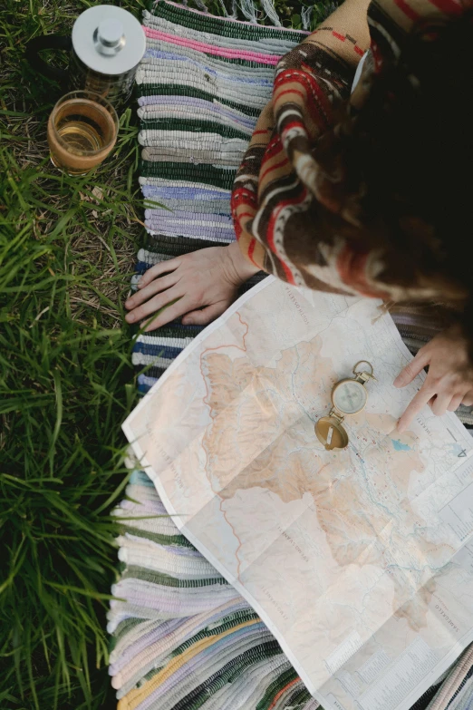 a woman sitting on a blanket looking at a map, by Jessie Algie, trending on unsplash, square, top down shot, compass, spring season