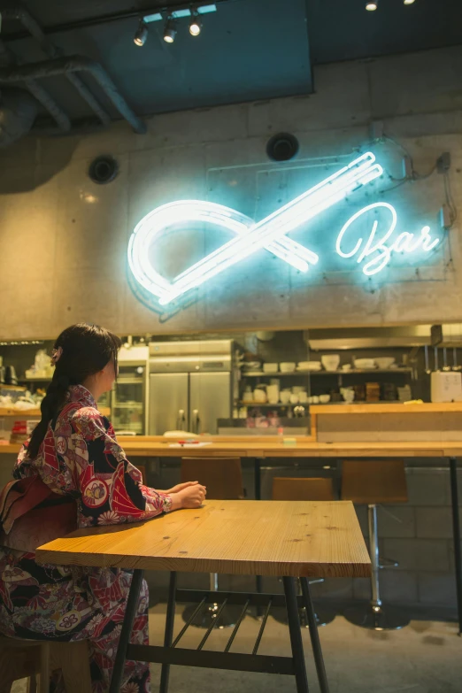 a woman sitting at a table in front of a neon sign, by Sengai, pexels, at the counter, infinity symbol, in tokio, blank