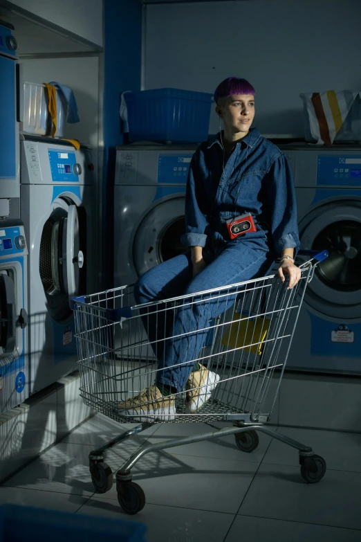 a woman sitting in a shopping cart in a laundry room, a portrait, pexels contest winner, renaissance, wearing human air force jumpsuit, worksafe. dramatic, (night), non-binary