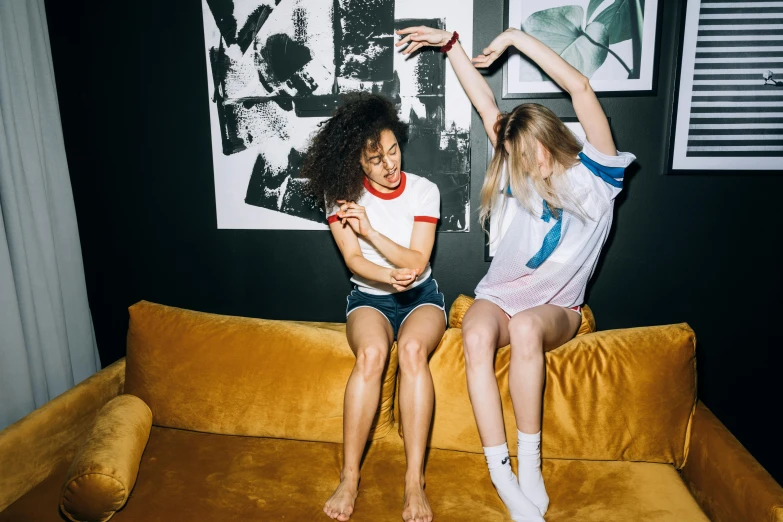 a couple of women sitting on top of a couch, inspired by Nan Goldin, trending on unsplash, kitsch movement, fists in the air, wearing shorts and t shirt, ying and yang, people dancing