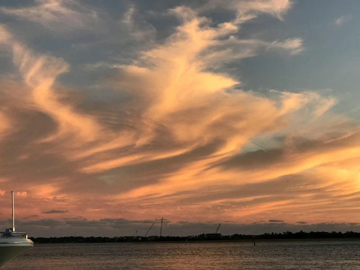 a boat sitting on top of a body of water, by Susy Pilgrim Waters, pexels contest winner, romanticism, cirrus clouds, sunset panorama, upon a peak in darien, whorl. clouds