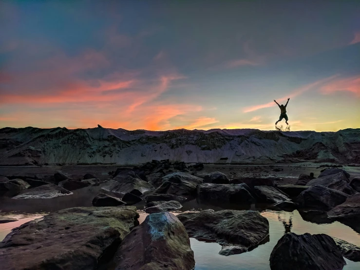 a man flying through the air while riding a skateboard, by Jesper Knudsen, unsplash contest winner, surrealism, bisti badlands, at the beach on a sunset, rock pools, jumping for joy