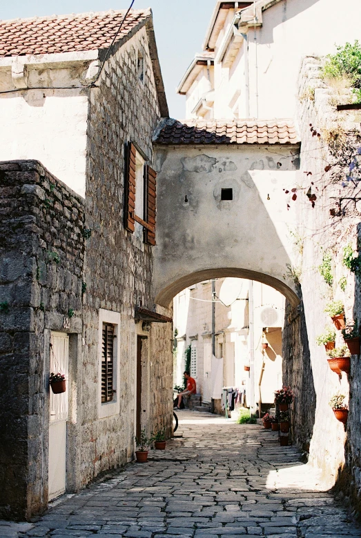 a narrow cobblestone street in an old town, pexels contest winner, romanesque, white stone arches, kodak portra film, croatian coastline, cottages