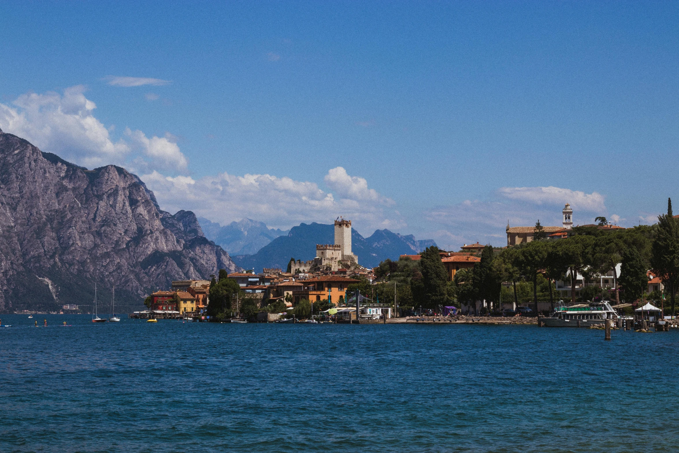 a large body of water with mountains in the background, inspired by Niccolò dell' Abbate, pexels contest winner, beautiful small town, conde nast traveler photo, lakeside, tall stone spires