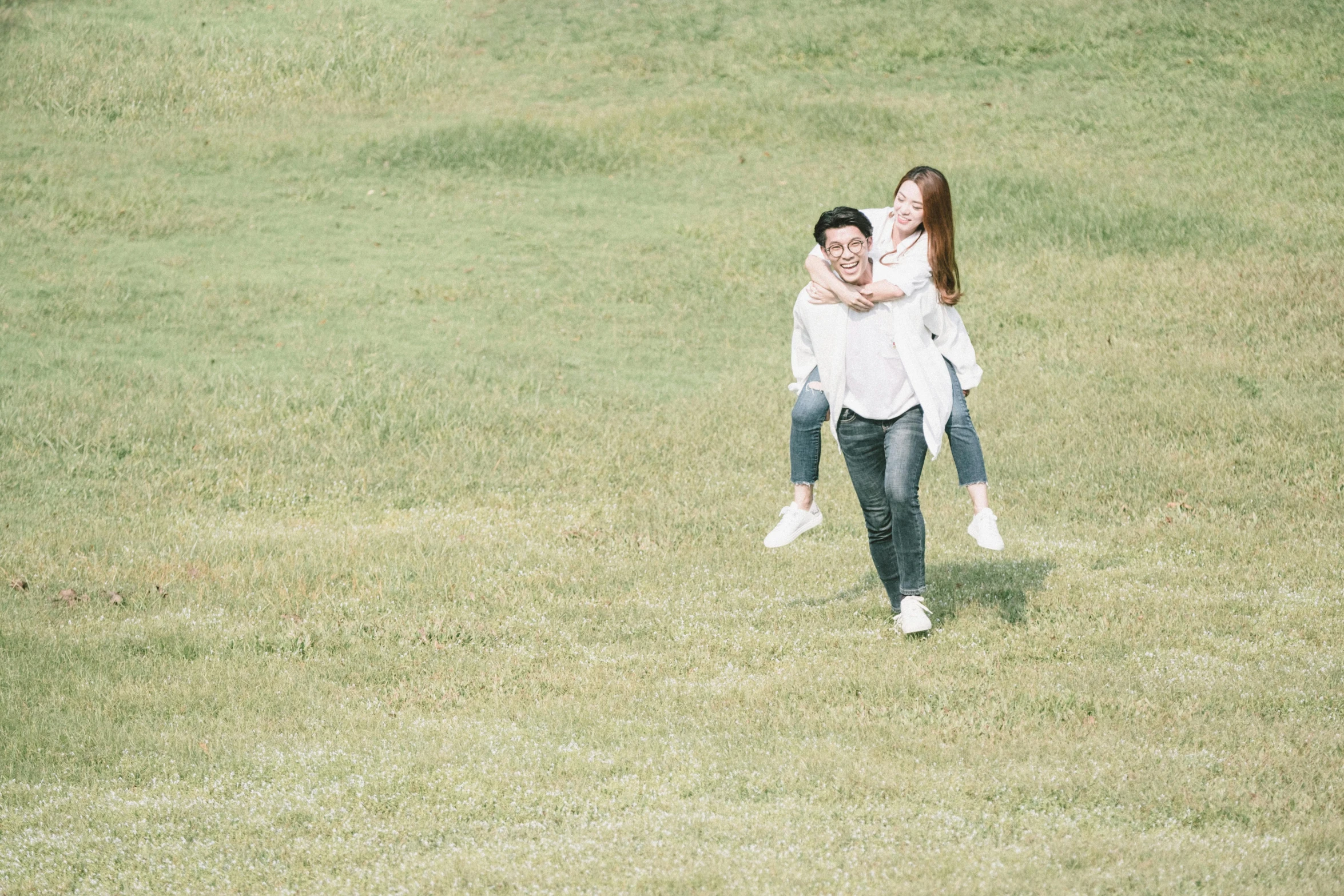 a man carrying a woman on his back in a field, by Tan Ting-pho, pexels contest winner, happening, walking at the park, white hue, on a green lawn, 15081959 21121991 01012000 4k