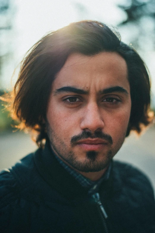 a close up of a person wearing a jacket, inspired by Khalil Gibran, pexels contest winner, mid long hair, arab man, square masculine facial features, concerned expression