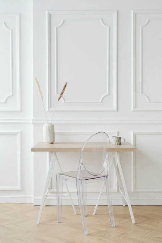 a wooden table with a clear chair in front of a white wall, trending on pexels, made out of clear plastic, dwell, set photo, white pearlescent
