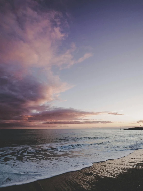 a large body of water sitting on top of a sandy beach, unsplash, romanticism, pink storm clouds, manly, ((sunset)), big overcast