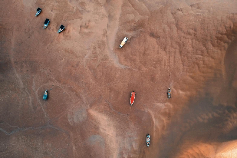 a group of boats sitting on top of a sandy beach, by Adam Marczyński, pexels contest winner, land art, on the surface of mars, thumbnail, red river, surface blemishes