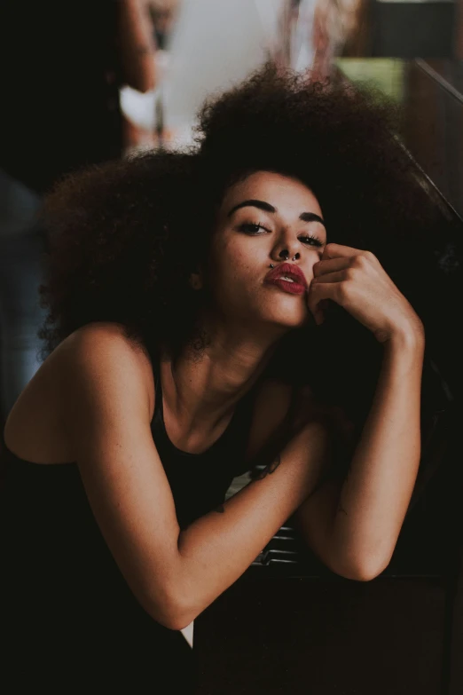 a woman sitting in front of a mirror brushing her hair, pexels contest winner, ashteroth, sleepy fashion model face, dark tone, mixed race