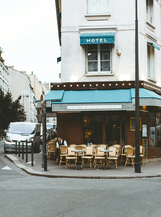 a street corner with tables and chairs in front of a hotel, a photo, pexels contest winner, wearing a french beret, youtube thumbnail, exterior view, storefront