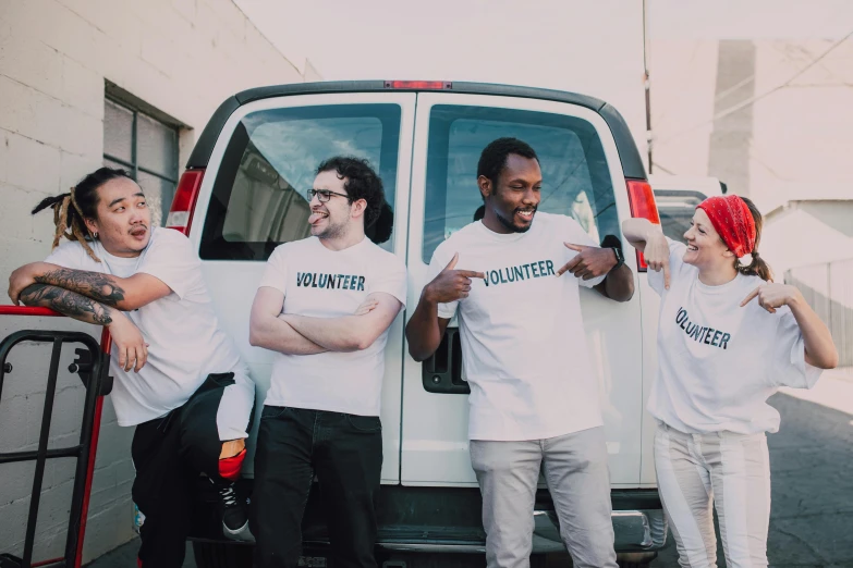 a group of people standing in front of a van, pexels contest winner, dressed in a white t shirt, smiling, avatar image, compassionate