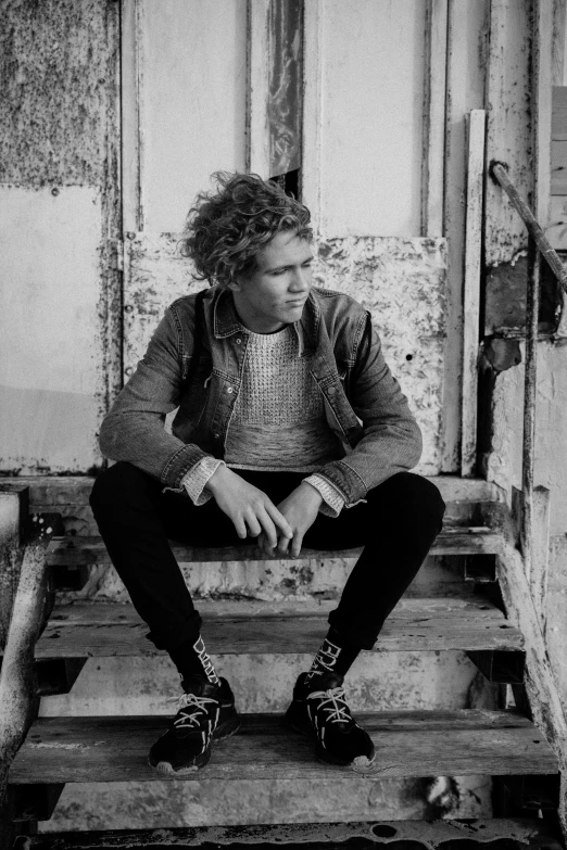 a black and white photo of a man sitting on a set of stairs, pale skin curly blond hair, (((rusty))), lachlan bailey, curly haired
