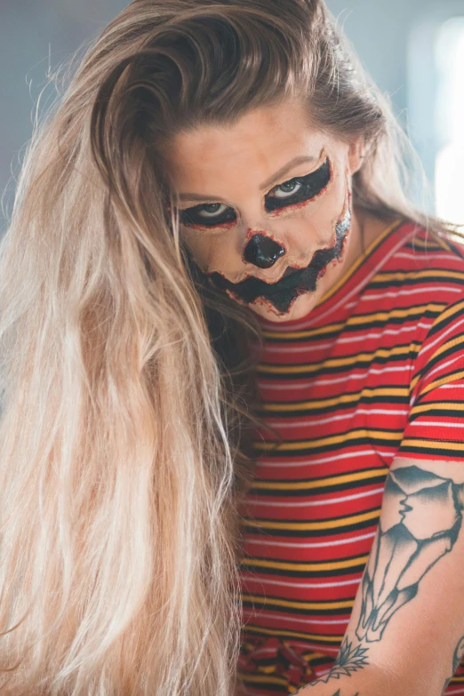 a woman with her face painted to look like a clown, inspired by Elsa Bleda, pumpkin head, hot topic, striped, a blond