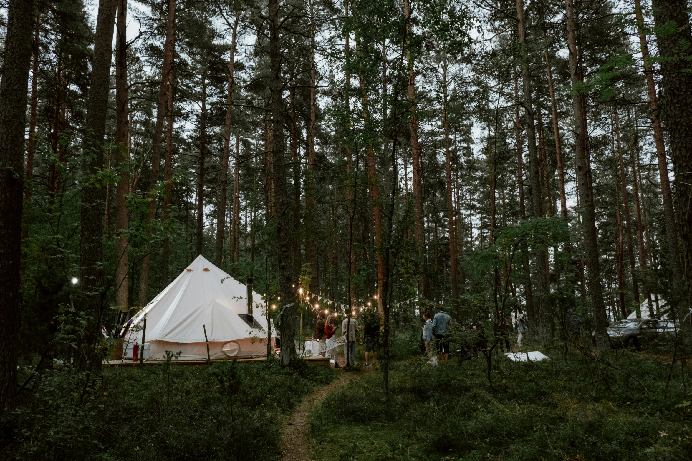 a white tent sitting in the middle of a forest, in style of heikala, cozy lighting, espoo, grey