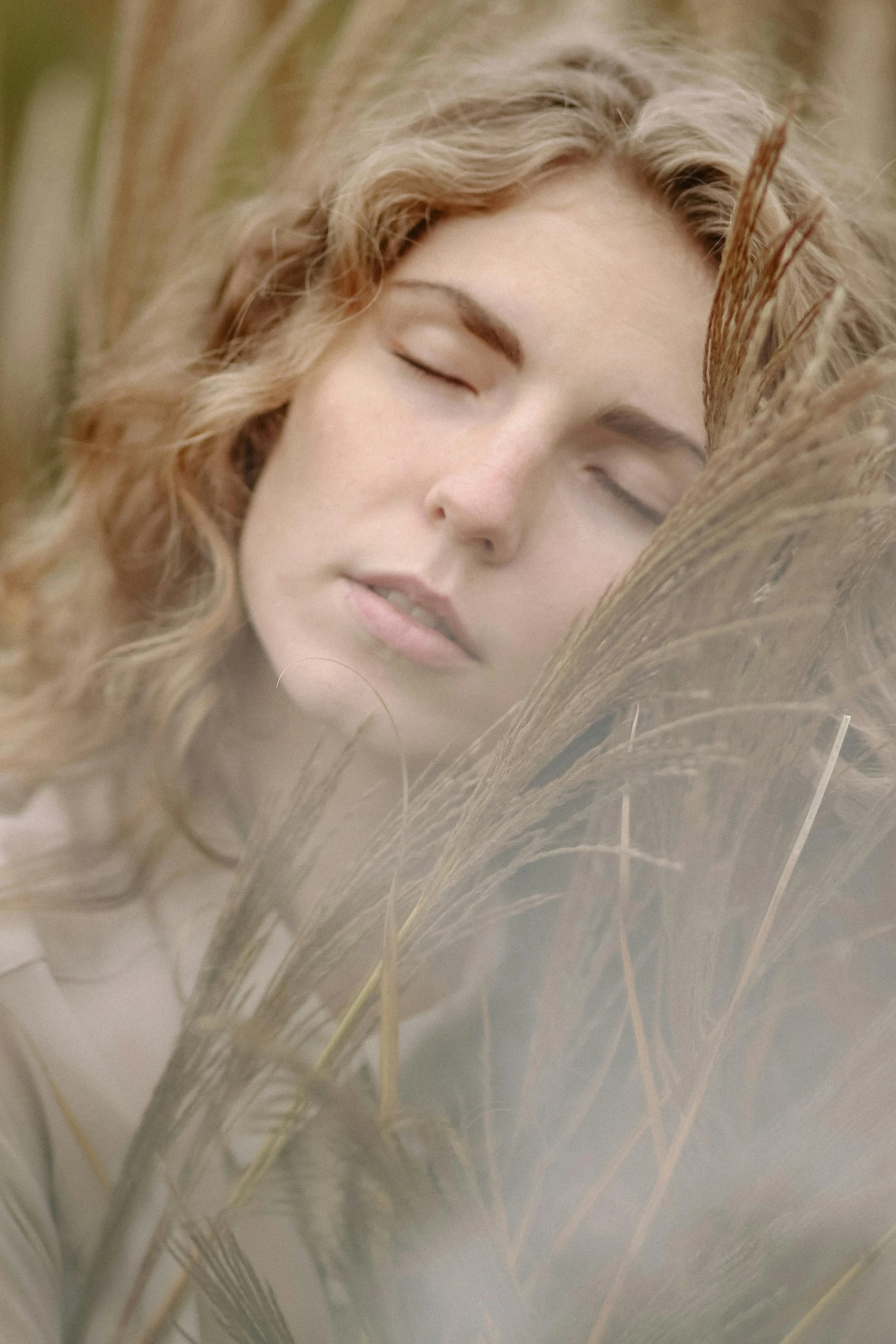 a woman that is laying down in the grass, inspired by Anna Füssli, unsplash, digital art, close-up portrait film still, wind and dust, subtle earthy tones, soft hair