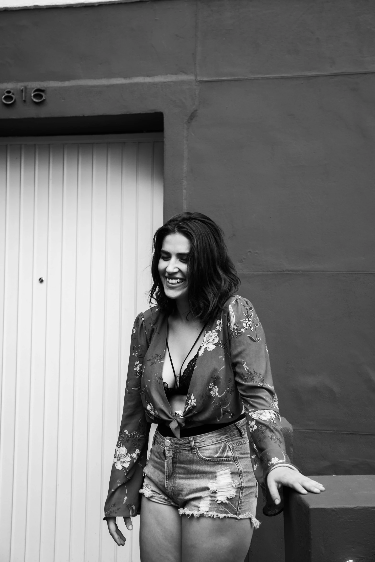 a woman standing in front of a garage door, a black and white photo, happy vibes, yennefer, charli bowater, laughter